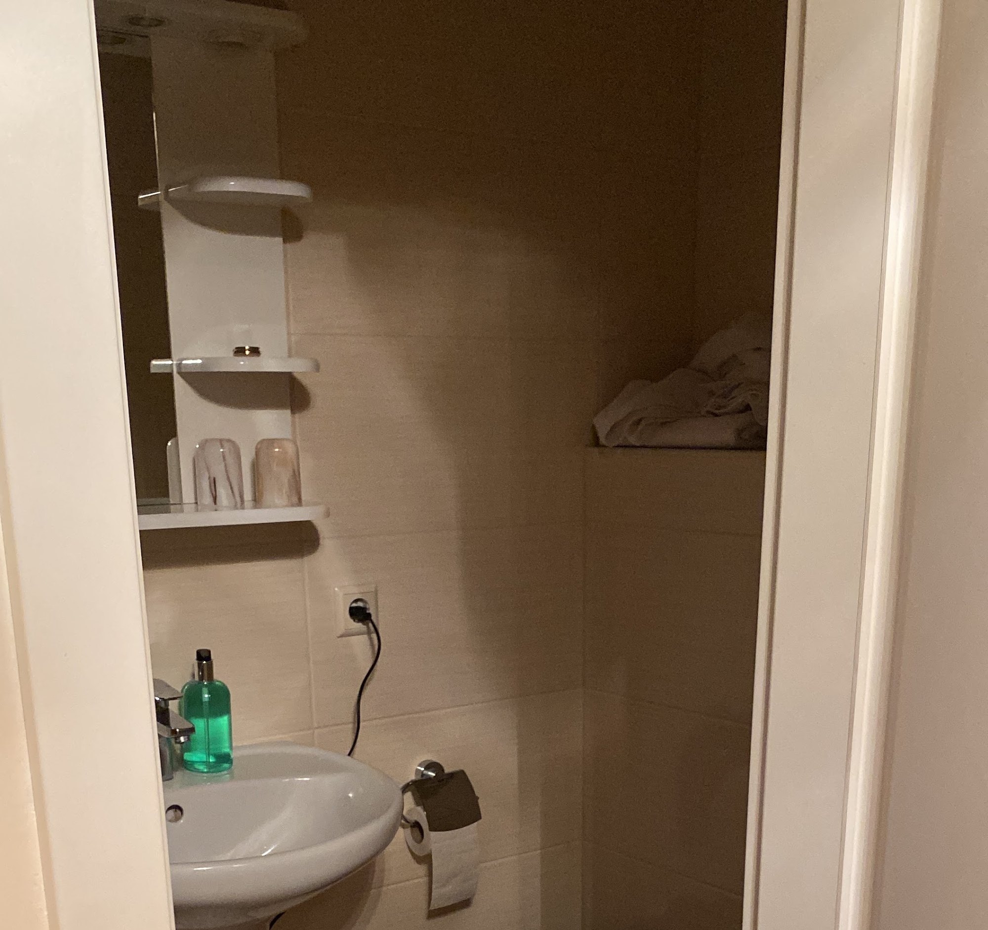 Gefliestes Bad mit Waschbecken und Spiegelregal
